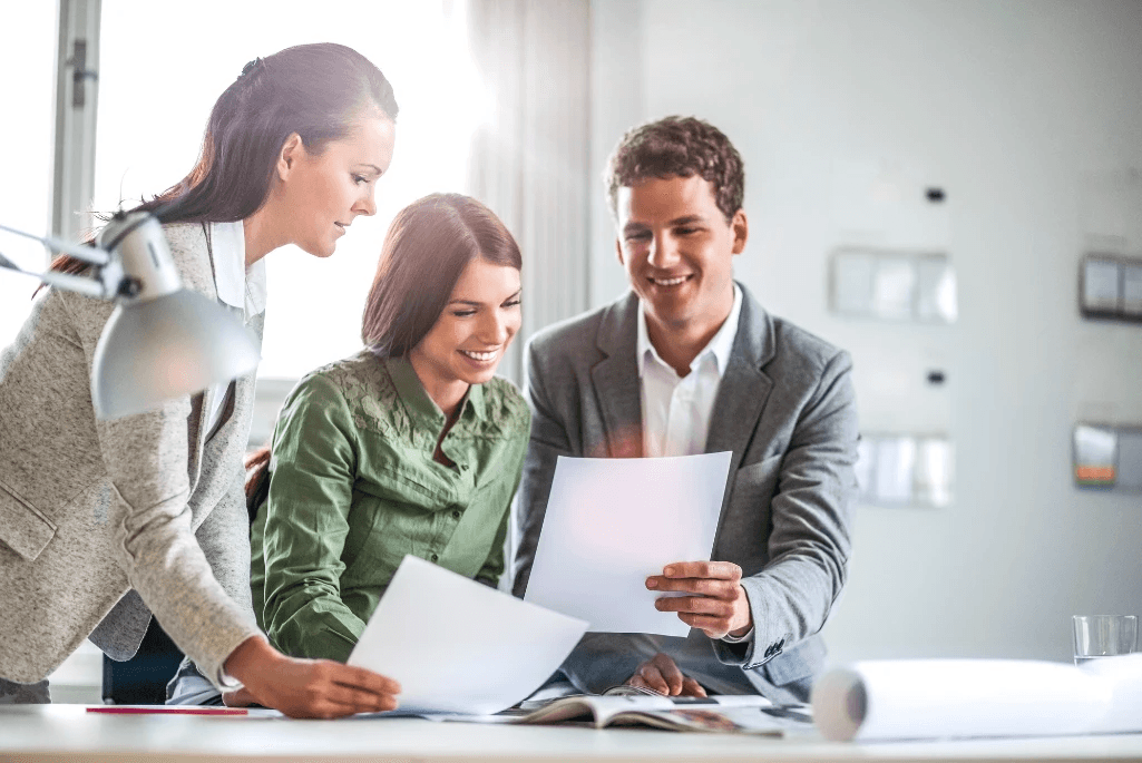 People in background discussing business with model apartment buildings on desk