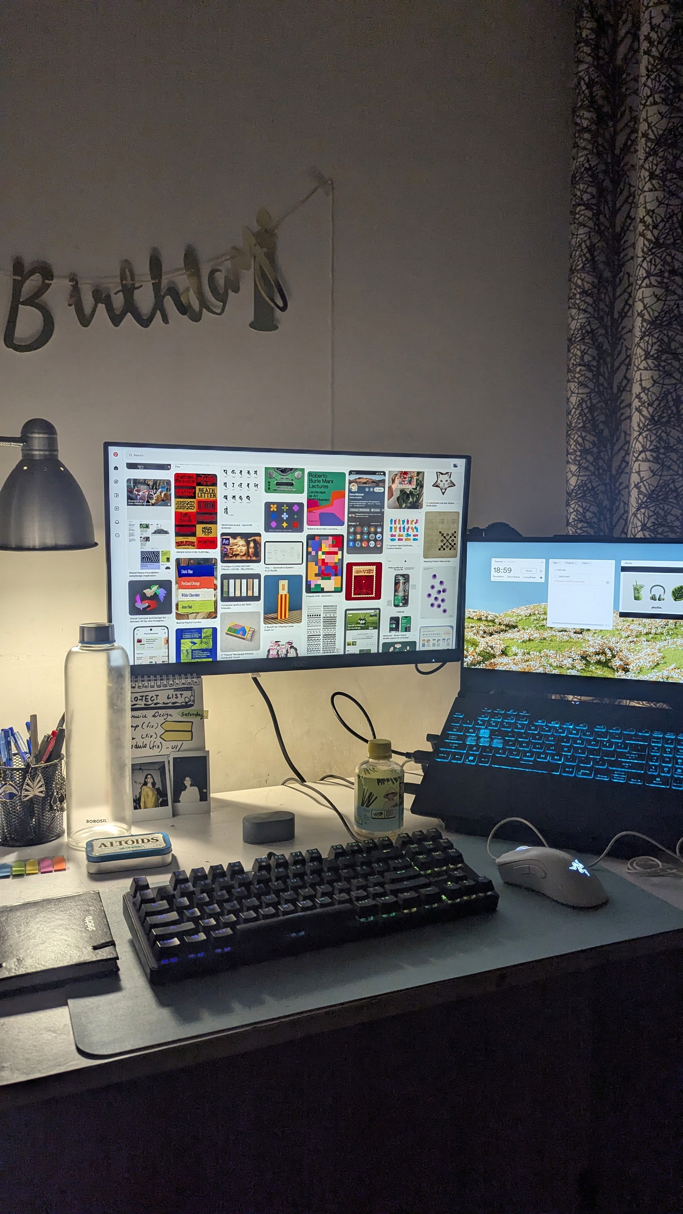 Modern home office setup with a monitor, ergonomic chair, keyboard, and indoor plants near a window with blinds.