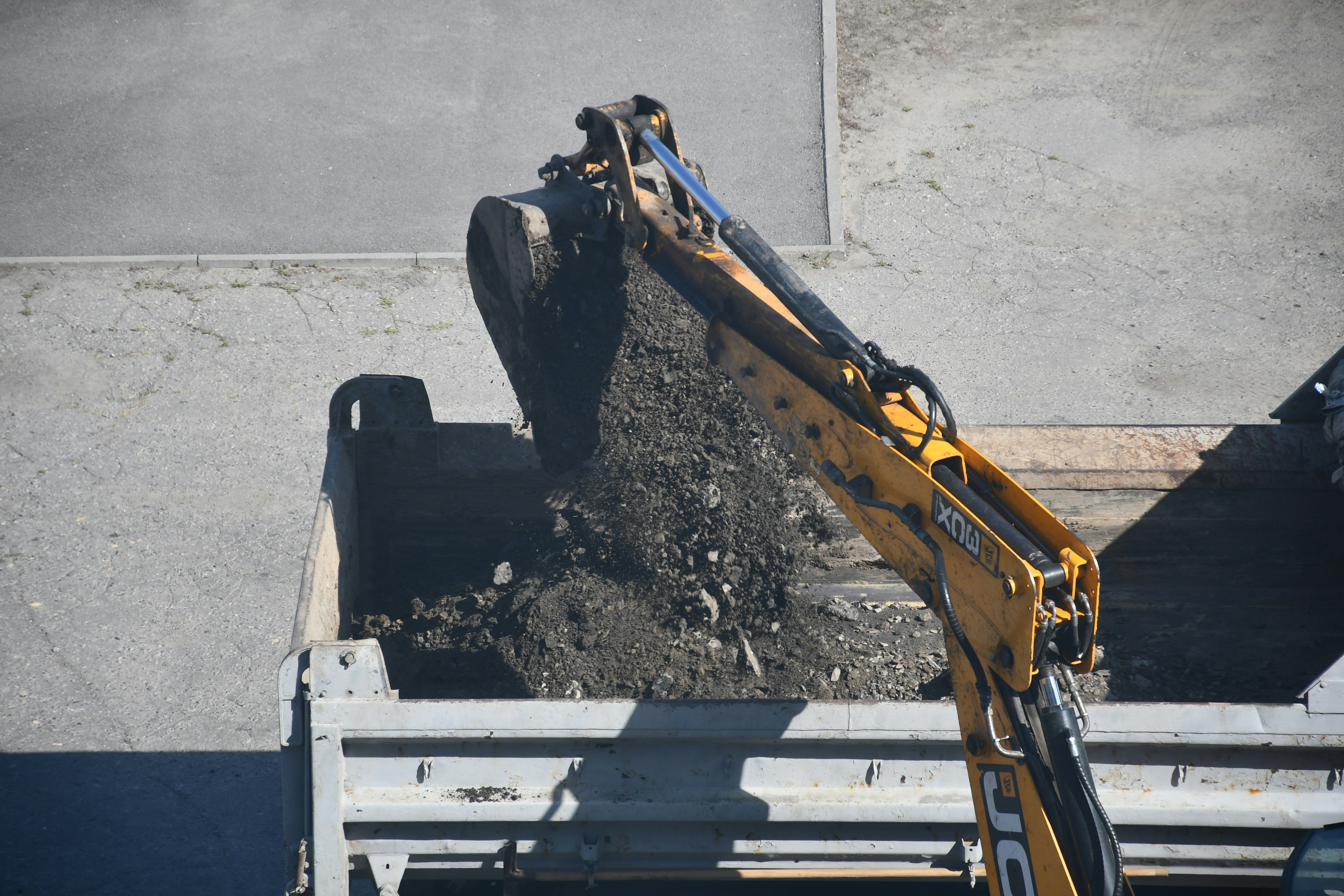 Excavatrice déposant de la terre dans la benne d’un camion lors de travaux d’excavation.