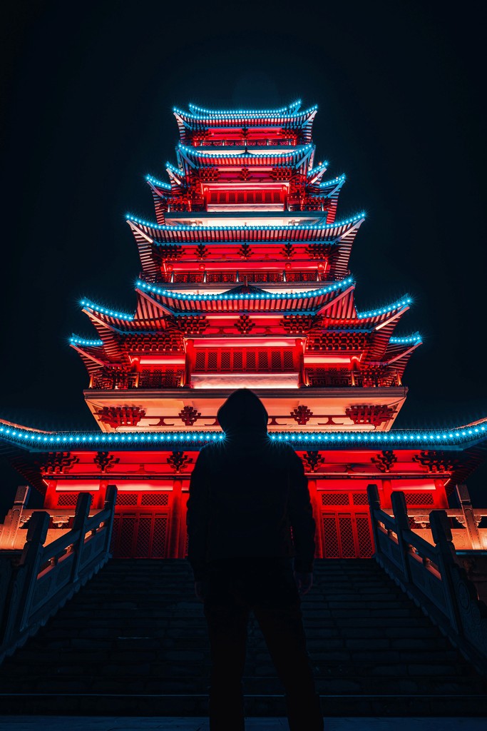 A person standing in front of a temple at night