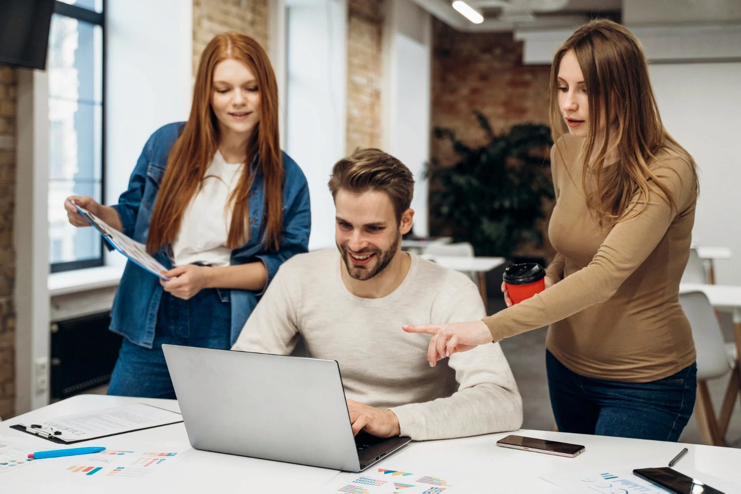 Web designers discussing website design ideas while working together at a computer.