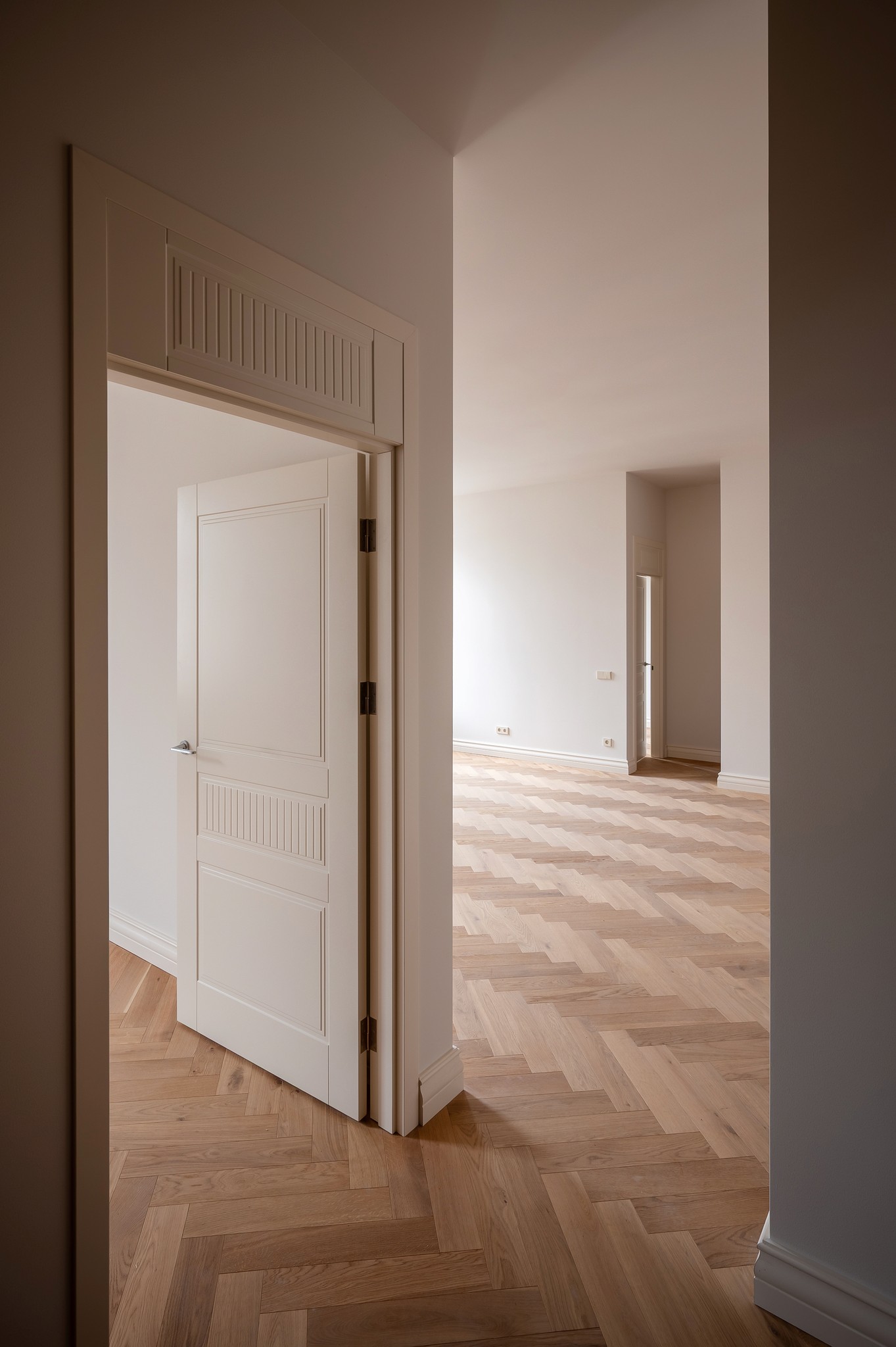 Row of modern white villas with balconies, surrounded by green grass under a clear blue sky.