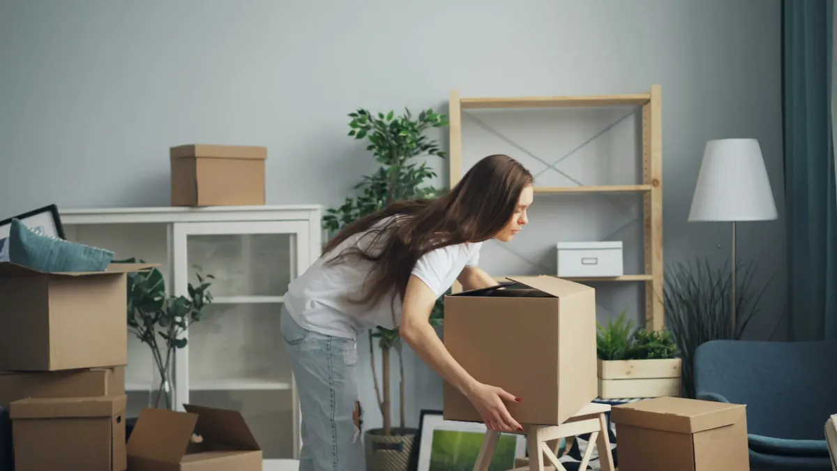 Joven desempaquetando cajas durante la mudanza a su nuevo piso. Seguro de inquilinos Allianz para asegurar tus muebles y responsabilidad civil.
