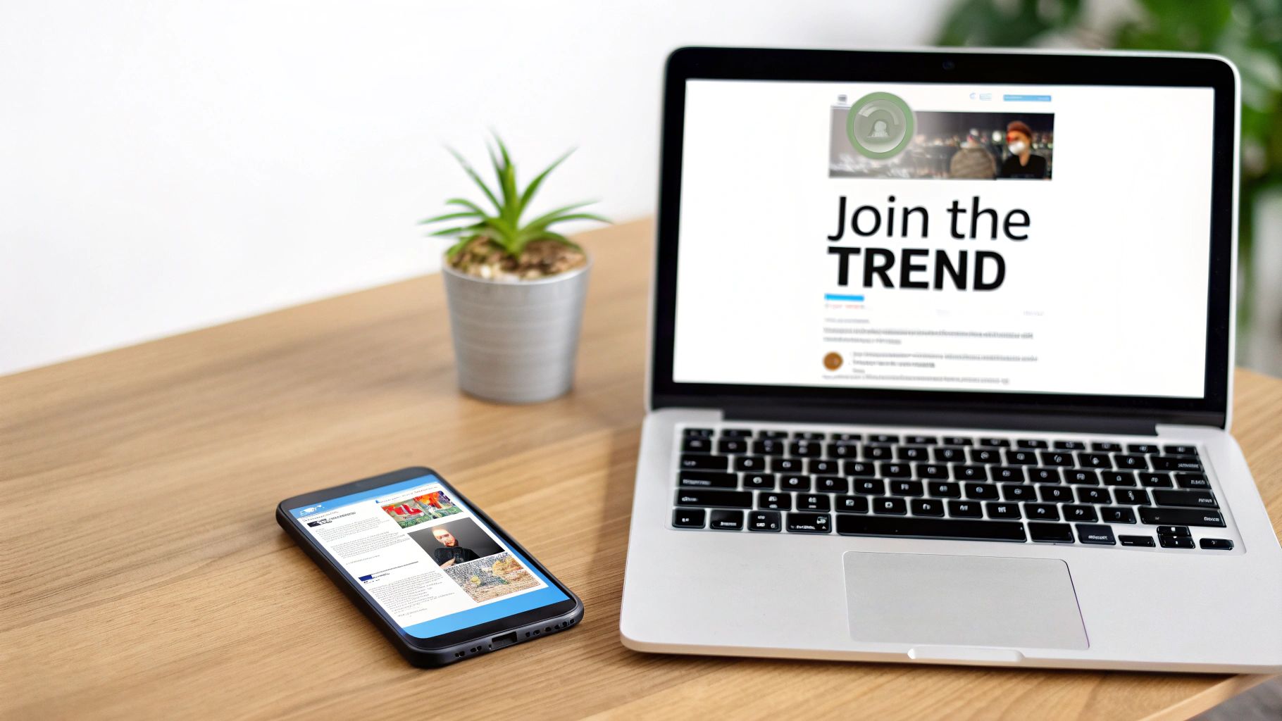 A laptop and smartphone display social media feeds on a wooden desk with a plant.