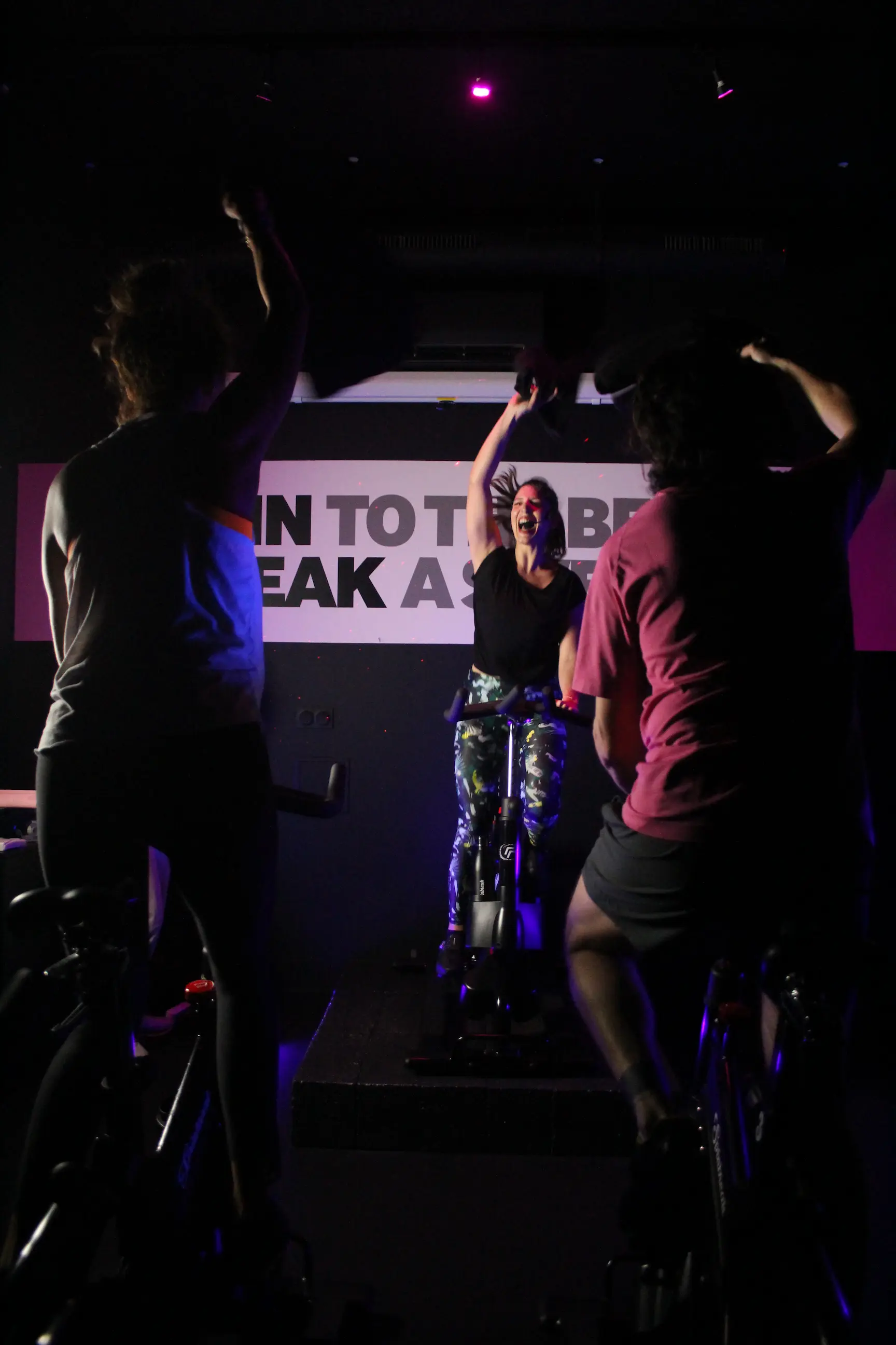 Coach et participants célébrant la fin d’une séance d’indoor cycling immersive chez Spinbreak à Bordeaux