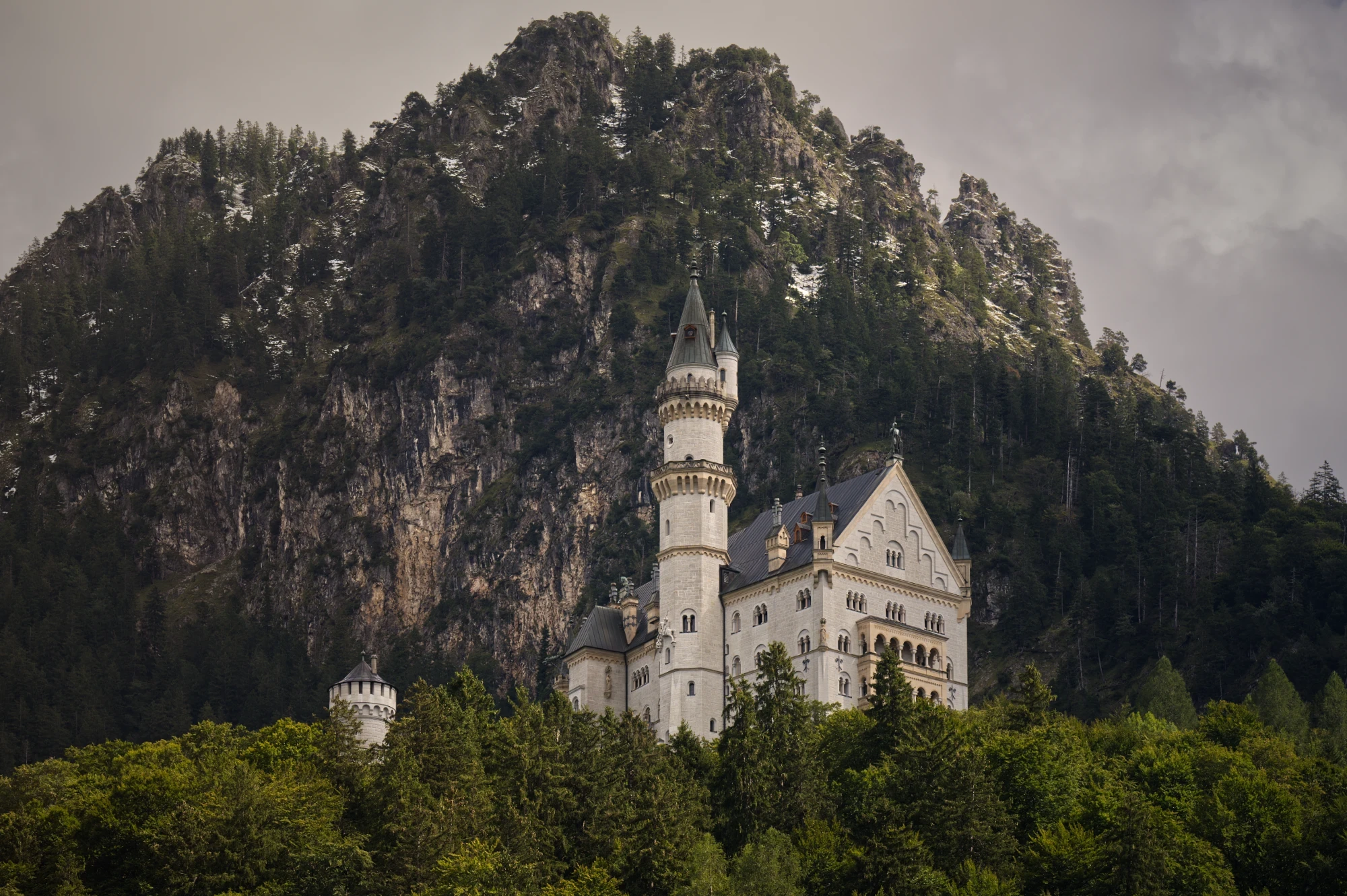 Schloss Neuschwanstein im markanten Profilschnitt vor einer steilen Felswand in den Bayerischen Alpen.