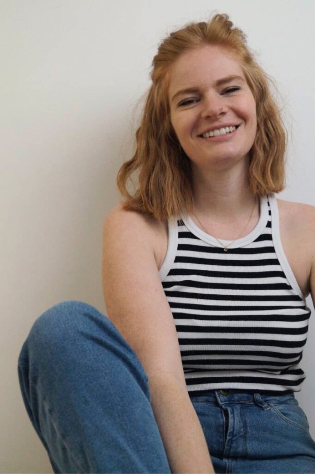 Bettina Hereth sitzend mit angewinkeltem Bein und lächelnd