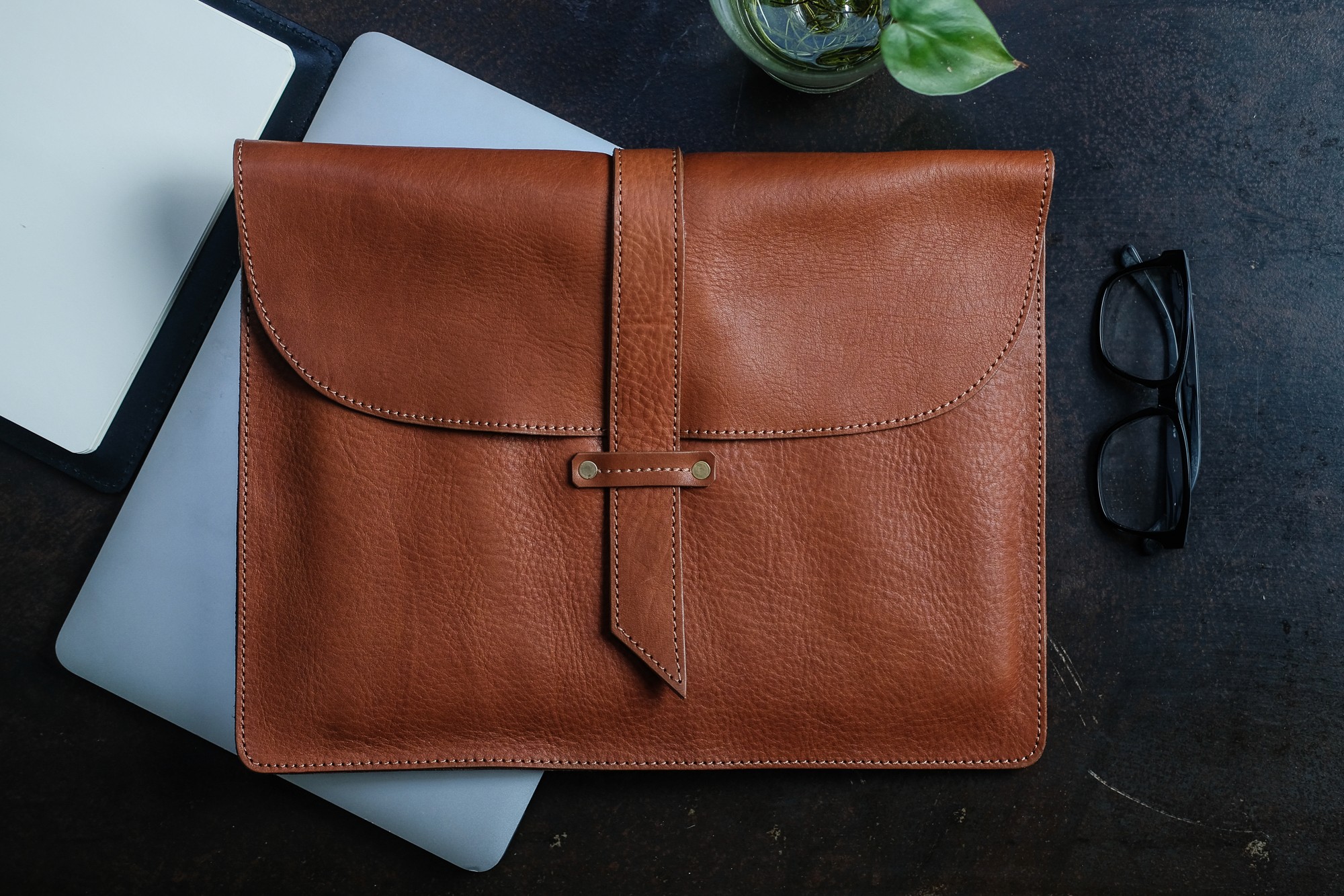 Close-up of a dark green leaf showing its textured surface and central vein against a muted background.
