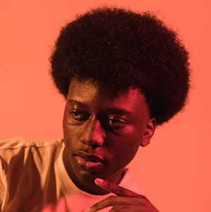 Man with afro and coral background.