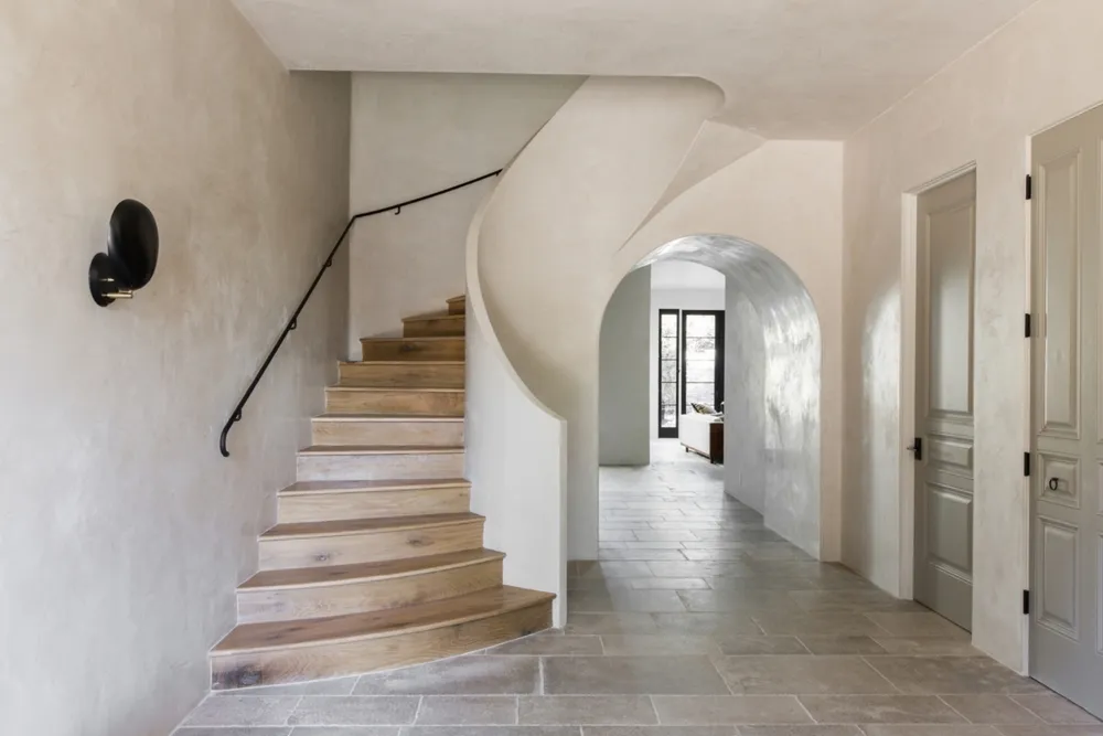 Large curving plaster staircase and arched casements leading into living room