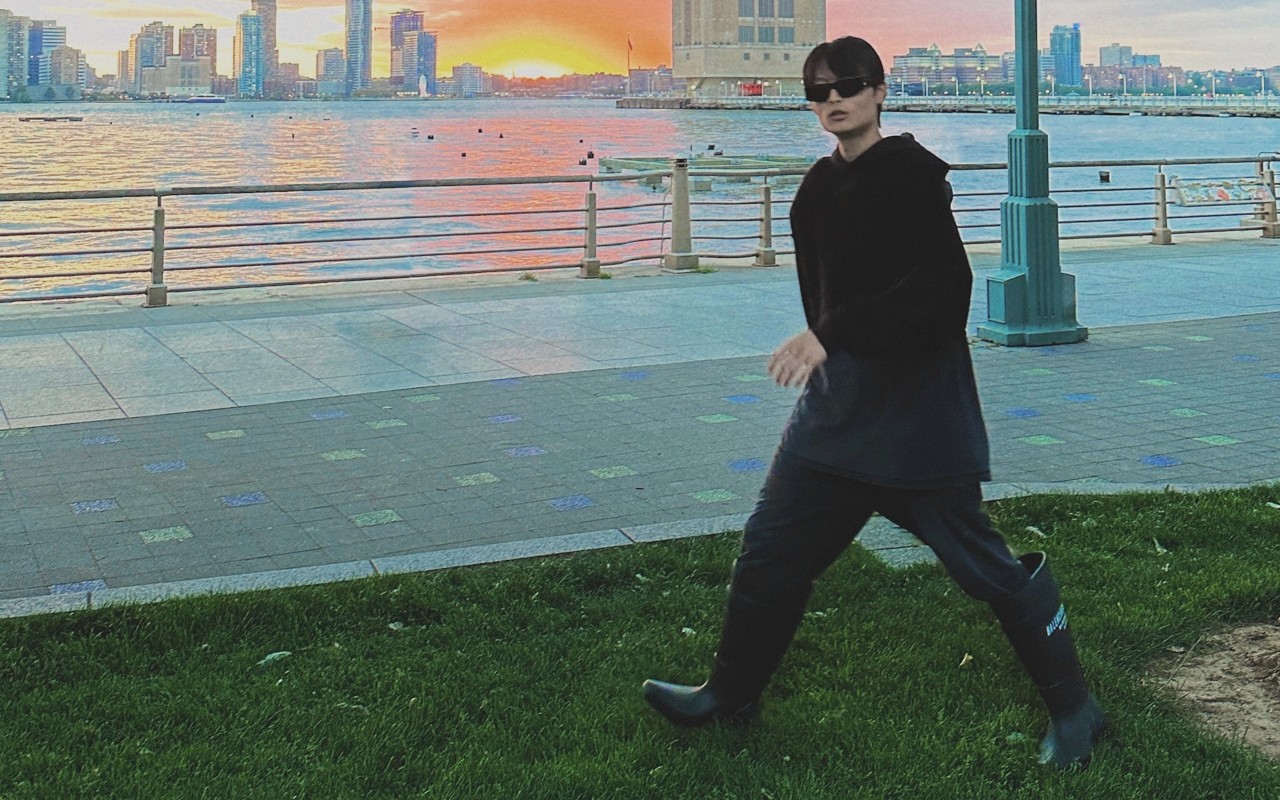man with sunglasses walkin in a park by a river