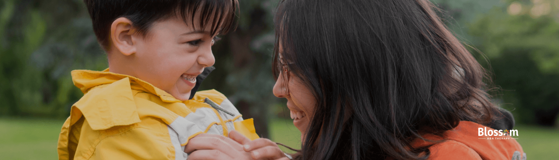 A mother and son smiling and laughing together outdoors.