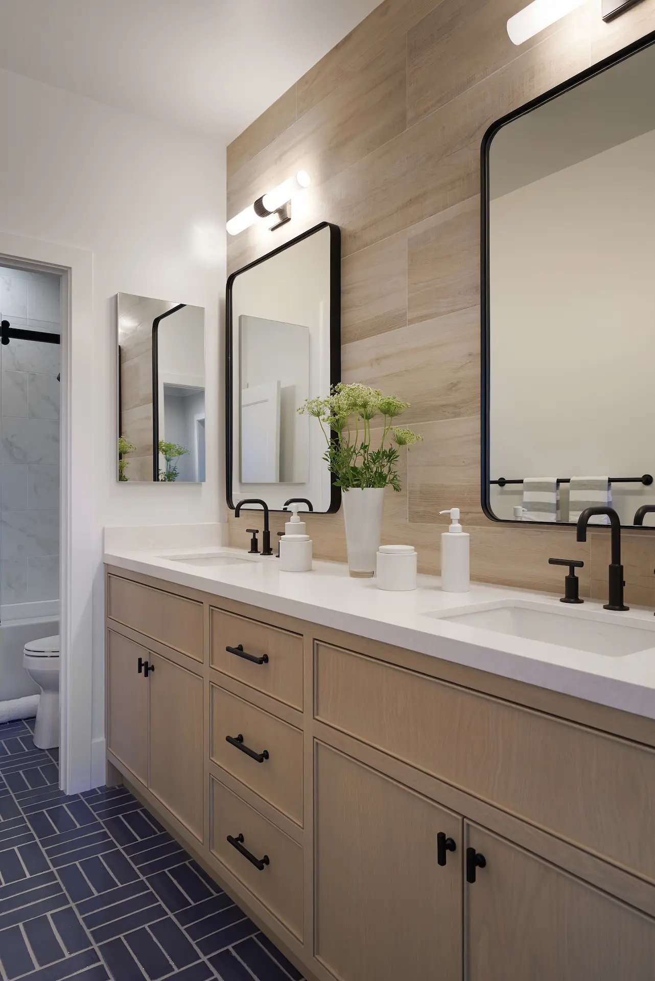 View of the double vanity in the kids' bathroom, featuring mirrors, sinks, and decor in the Irvine Contemporary Coastal Remodel. Photo by Todd Huge.