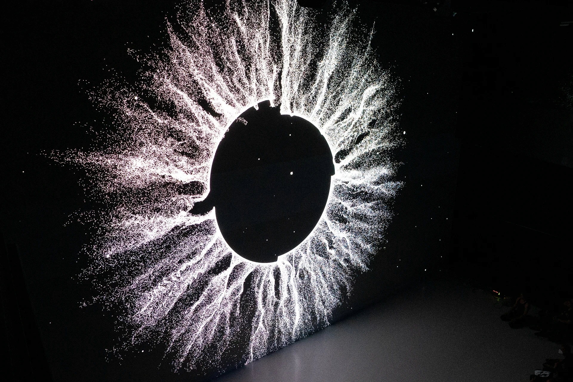 Black disk with glowing particles radiating outward