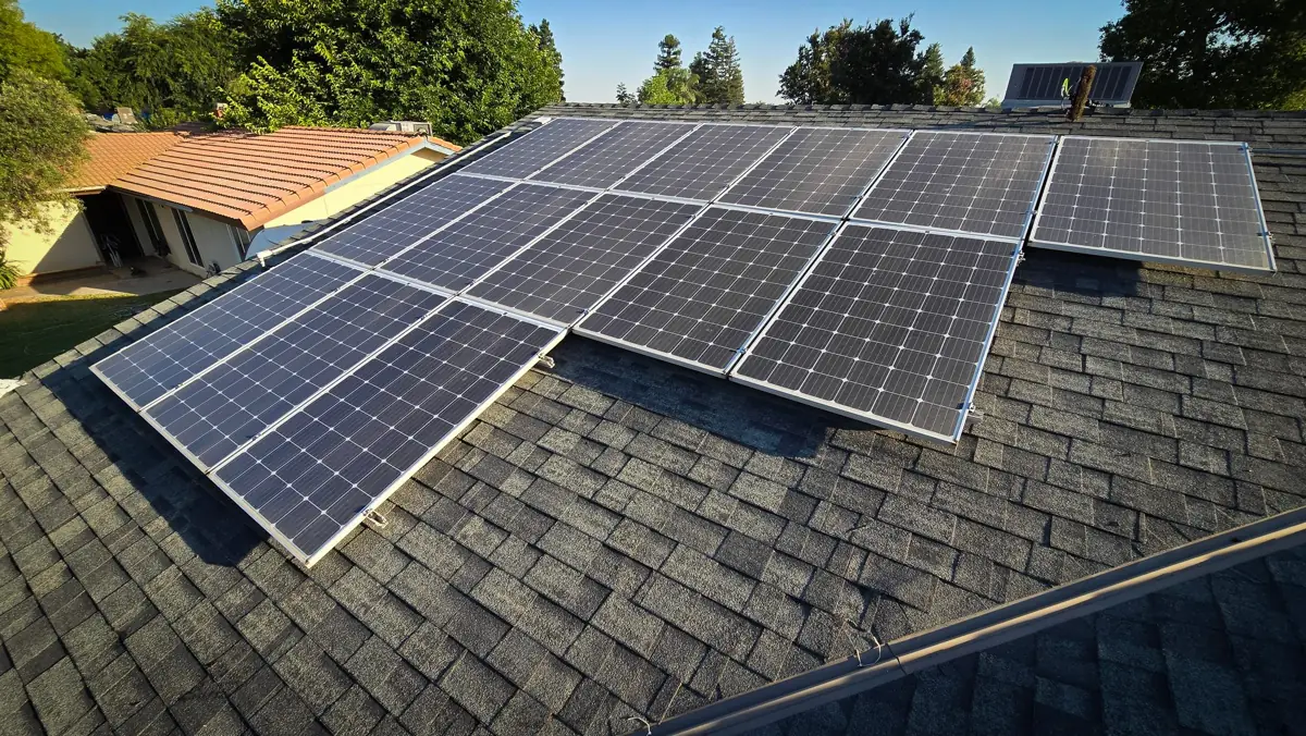 Solar panels on a shingle roof beside trees