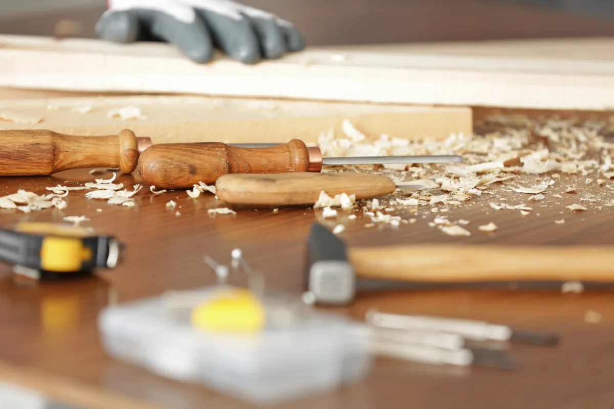 Établi de menuisier avec ciseaux à bois, copeaux et outils de chantier, artisans soigneusement sélectionnés pour les projets de rénovation Maud Ravetto Design