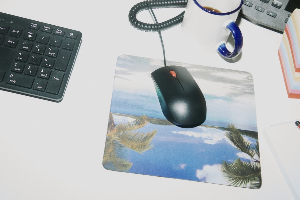 A computer mouse over a beach-themed mouse pad.