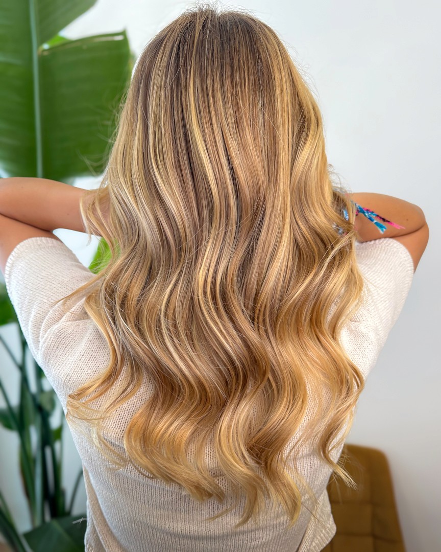 A luxurious bathtub filled with water and floating rose petals, surrounded by candles and greenery. The soft lighting creates a tranquil and romantic spa-like atmosphere.