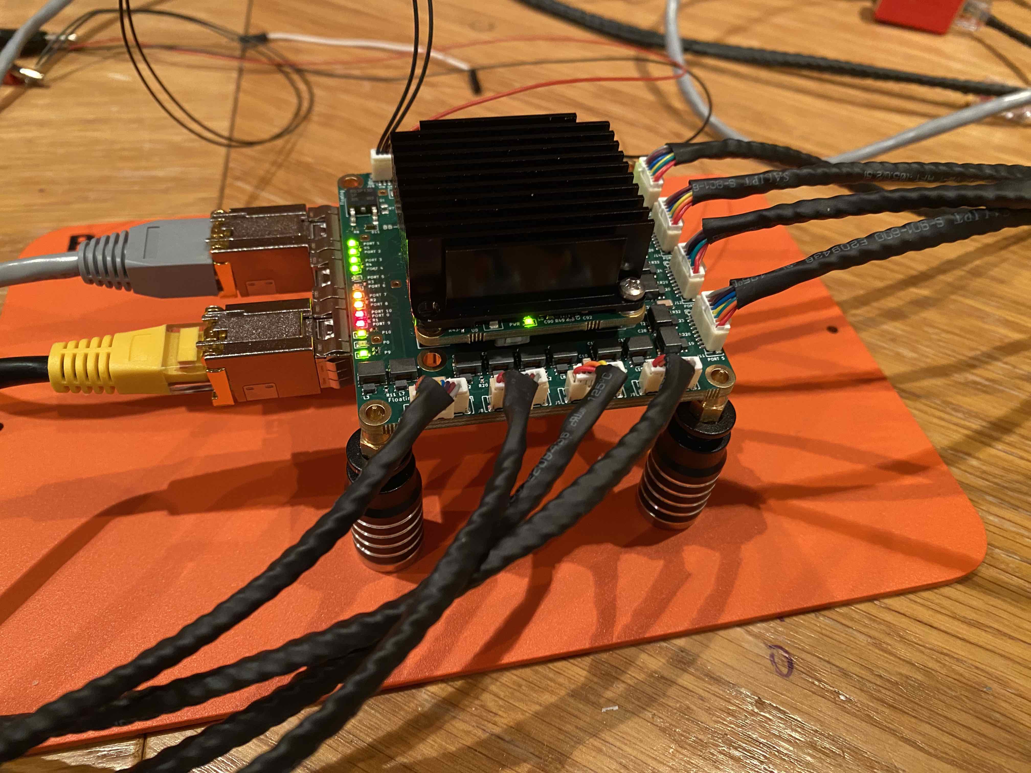 UbiSwitch bench setup with heatsink, active port LEDs, RJ45 uplinks and Picoblade cables before thermal testing