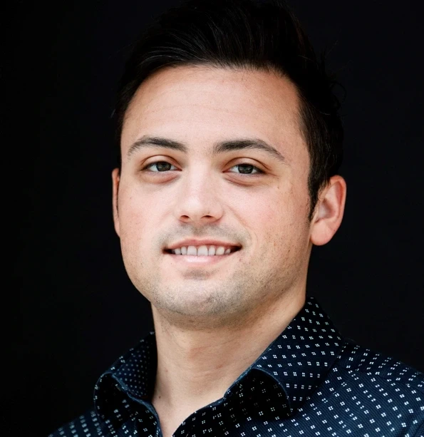 A thoughtful young person with dark hair gazes to the side, captured in soft black and white lighting.