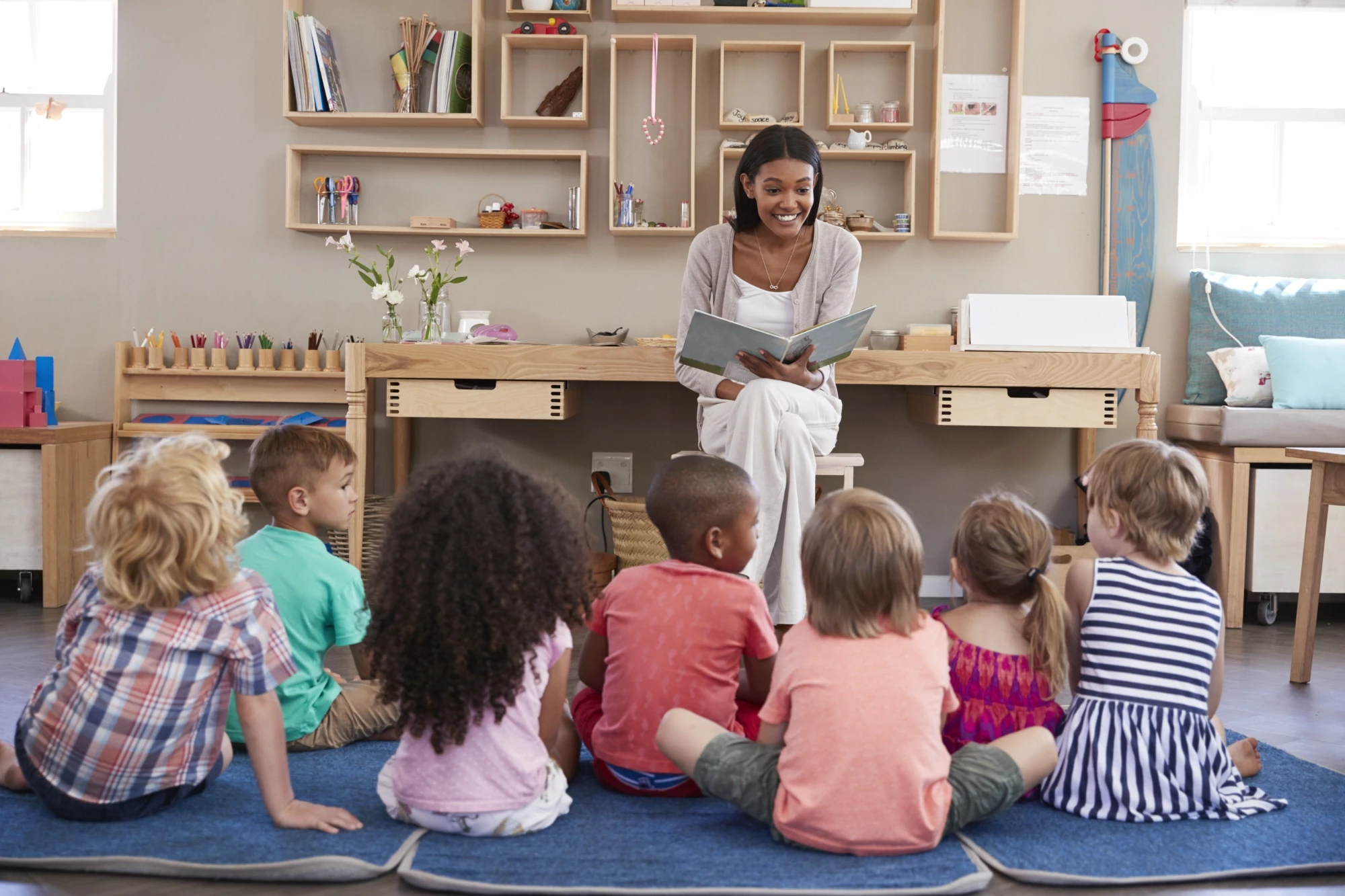 a teacher reading a book to her kids in classroom