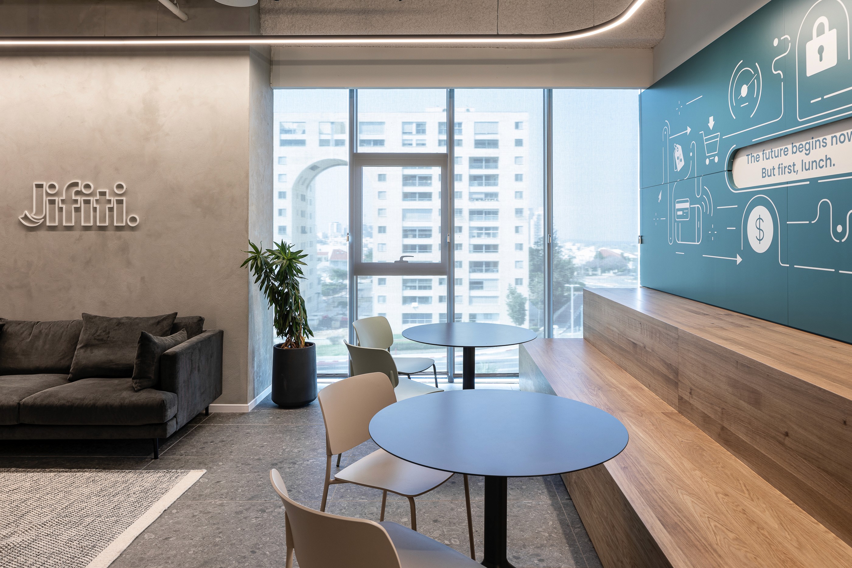 מיתוג סביבתי (Environmental Graphics): קיר כוח בגוון טורקיז עם איורים מעולם התוכן הפיננסי, לצד טריבונת ישיבה מעץ (Bleachers) להתכנסויות.