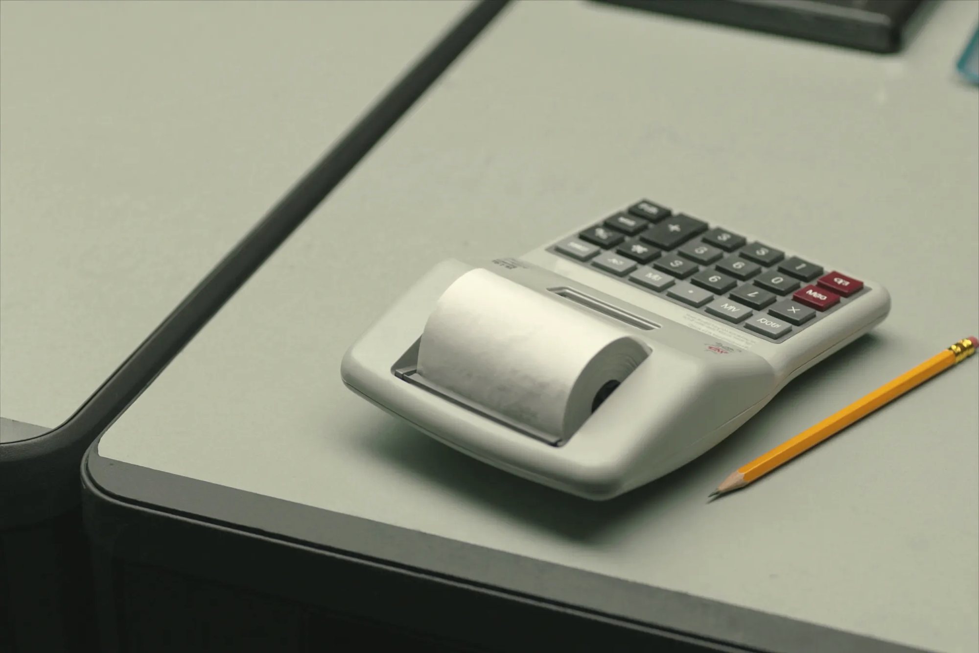 A receipt calculator and a pencil on a desk