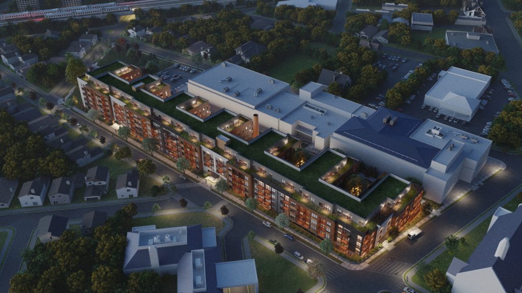 Twilight aerial view of a long, modern urban development featuring illuminated green rooftop terraces and courtyards, showcasing a large-scale M-Fire protected project.