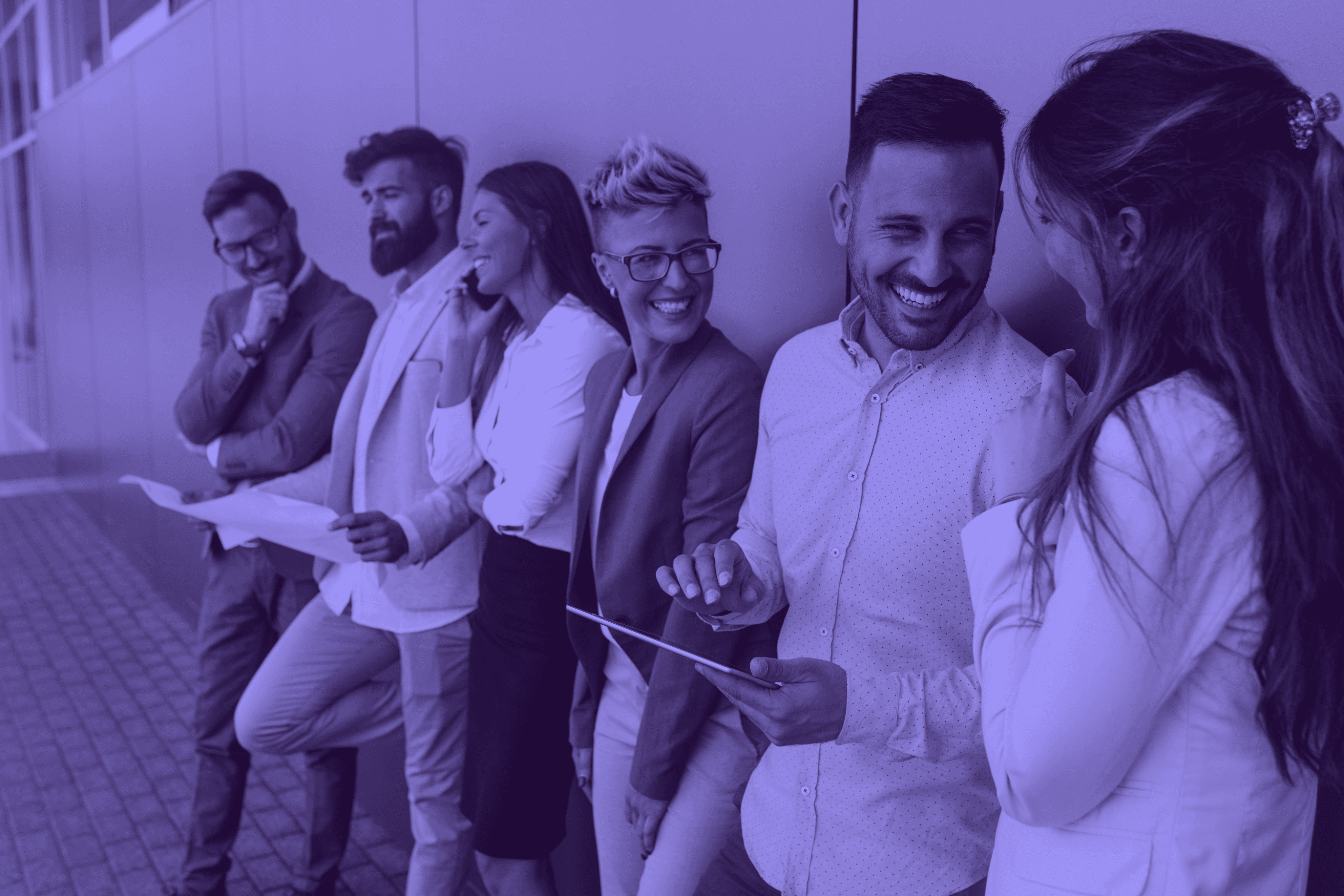 A diverse group of business individuals posing in front of a large commercial building.