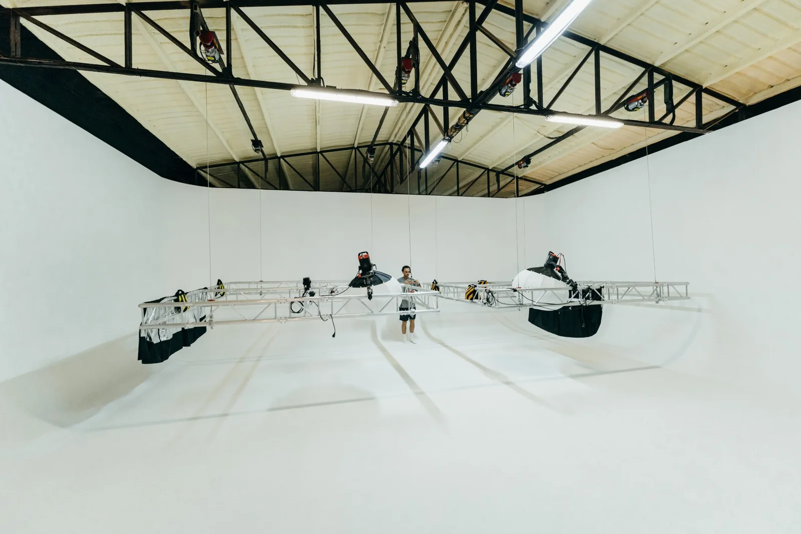 Truss frame with lights and diffusion suspended on motorized hoists above the white cyclorama