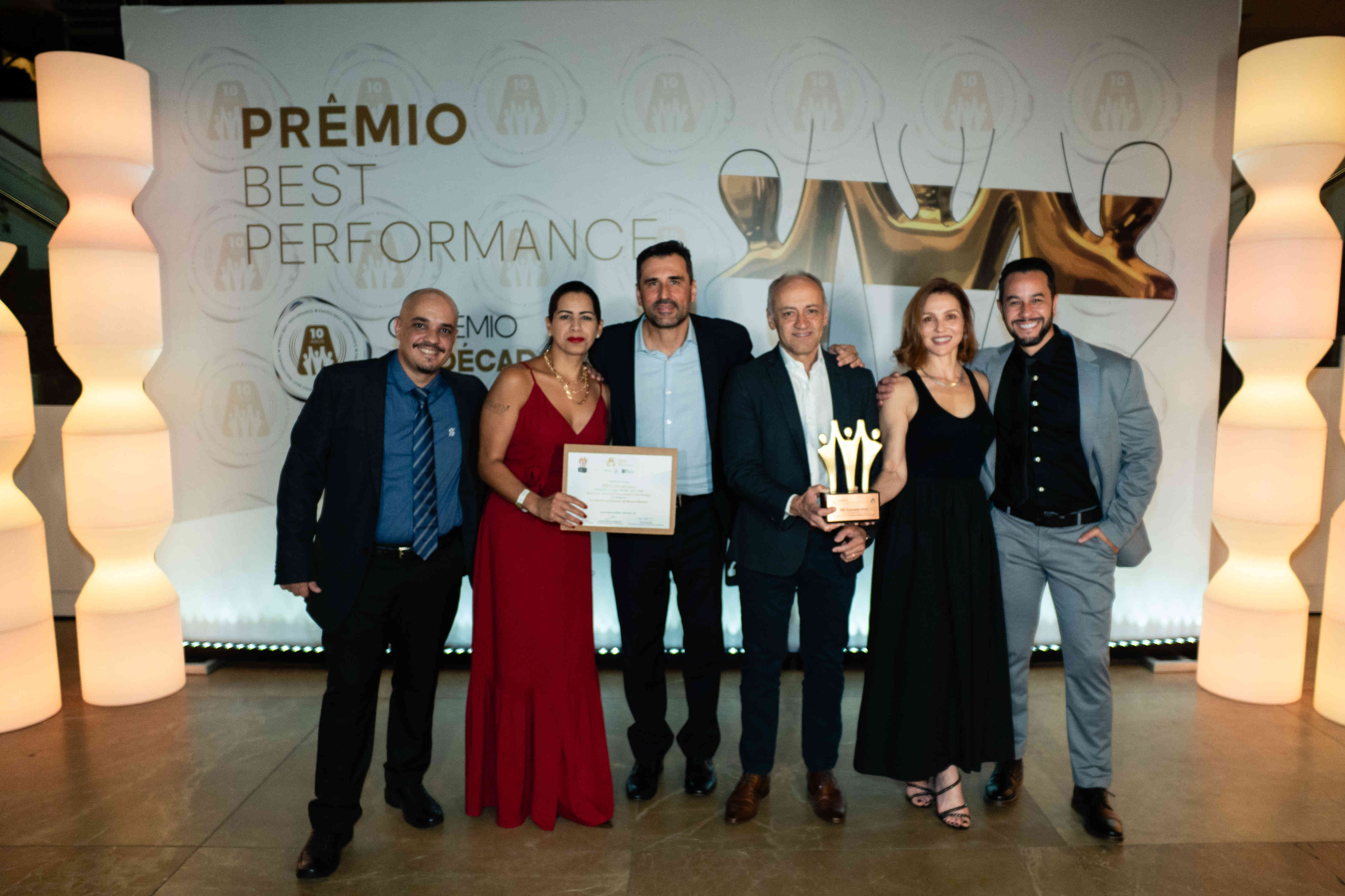 Executivos da BB Consórcios posando com troféu bronze e certificado no palco do Prêmio Best Performance 2025
