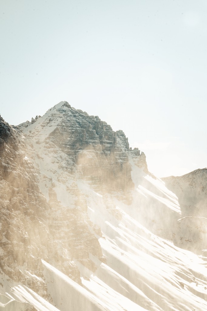 Snow-covered mountain peak with mist and sunlight.