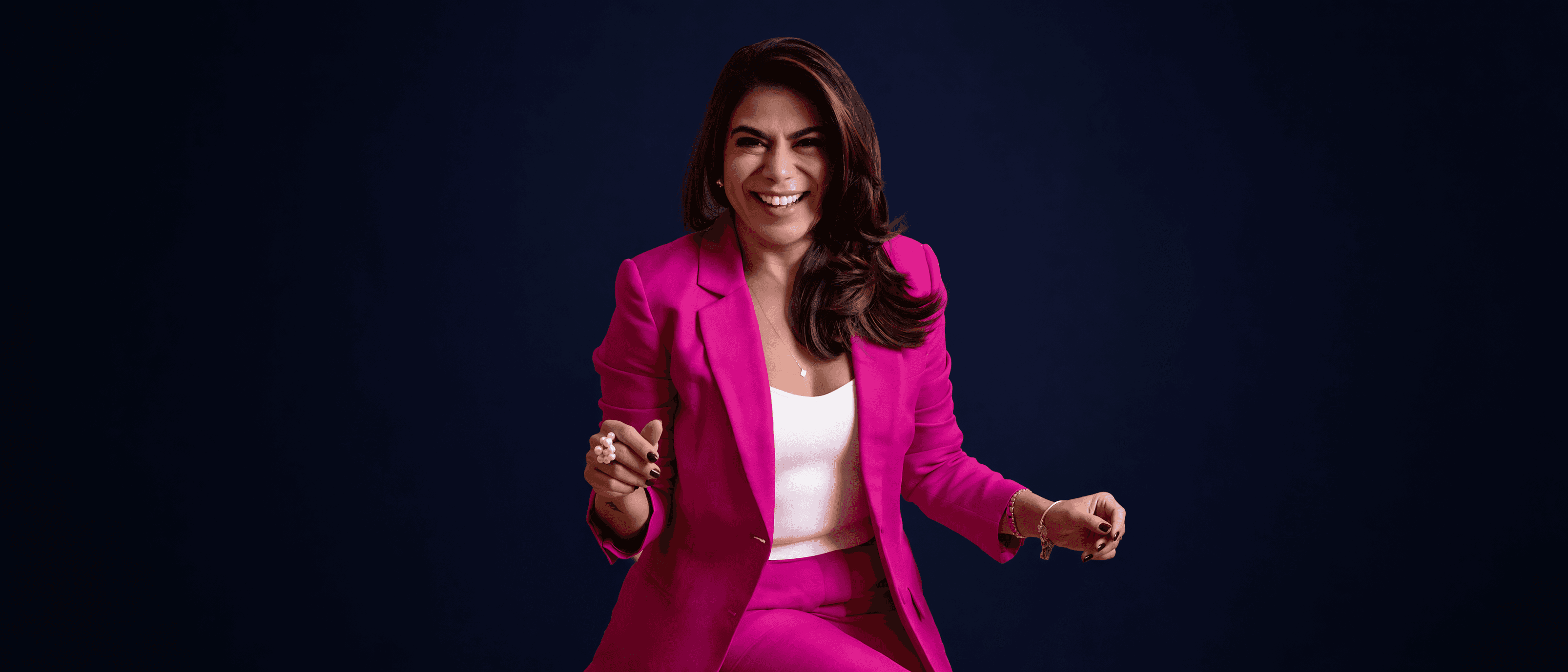 Milena Teles, estrategista em investimentos, sorrindo com blazer pink