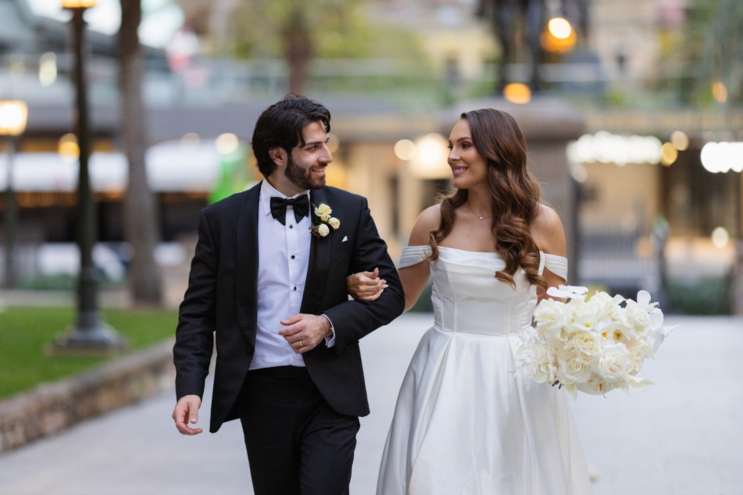Bride and groom walking down path looking at each other