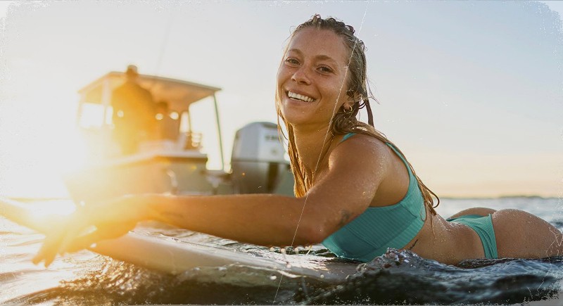 Photo of a woman paddling on a surfboard at sunset