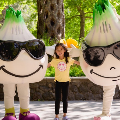 Seorang gadis kecil berdiri di antara maskot pembekal, Gil & Roy.
