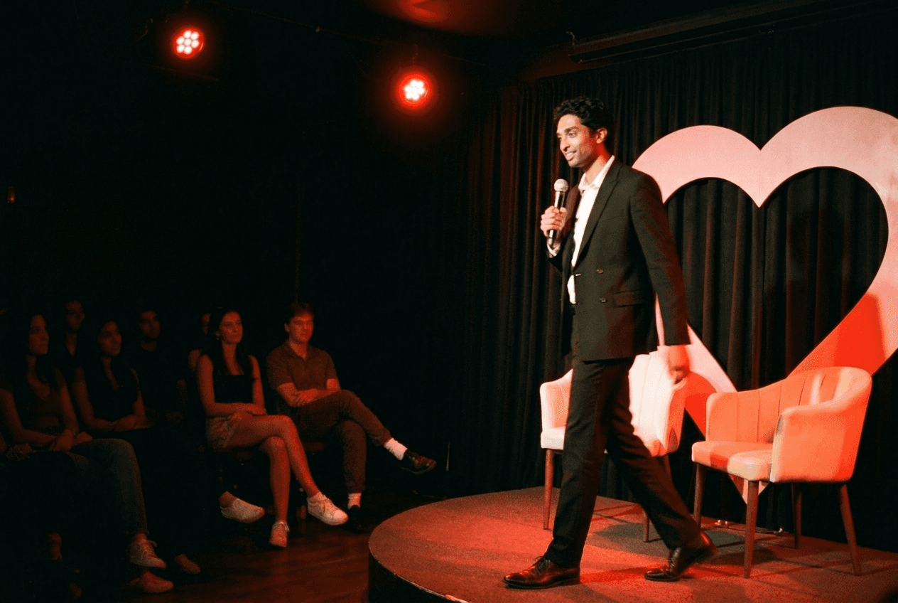 Concept image of the TAKE TWO host walking onstage in front of a heart-shaped backdrop.