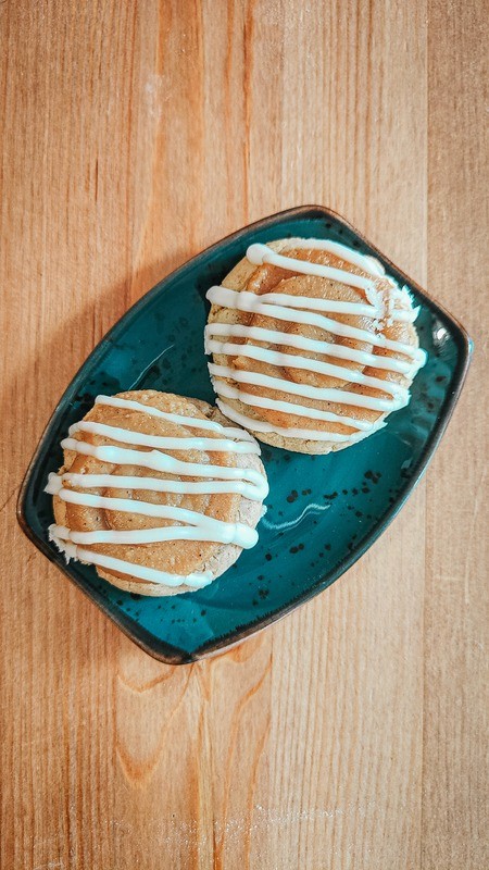 Two Manzana Borracha cookies on a plate , cinnamon apple cookies with caramel icing.