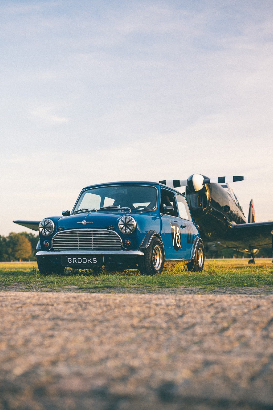 Close-up of a classic car's front, featuring round headlights and a sunset backdrop.