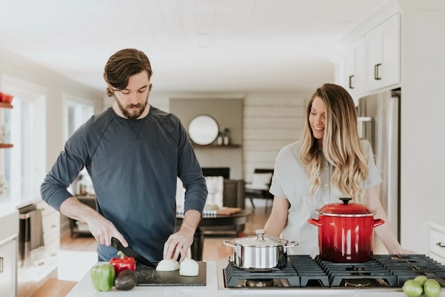 Man and woman preparing food together in a bright home kitchen.