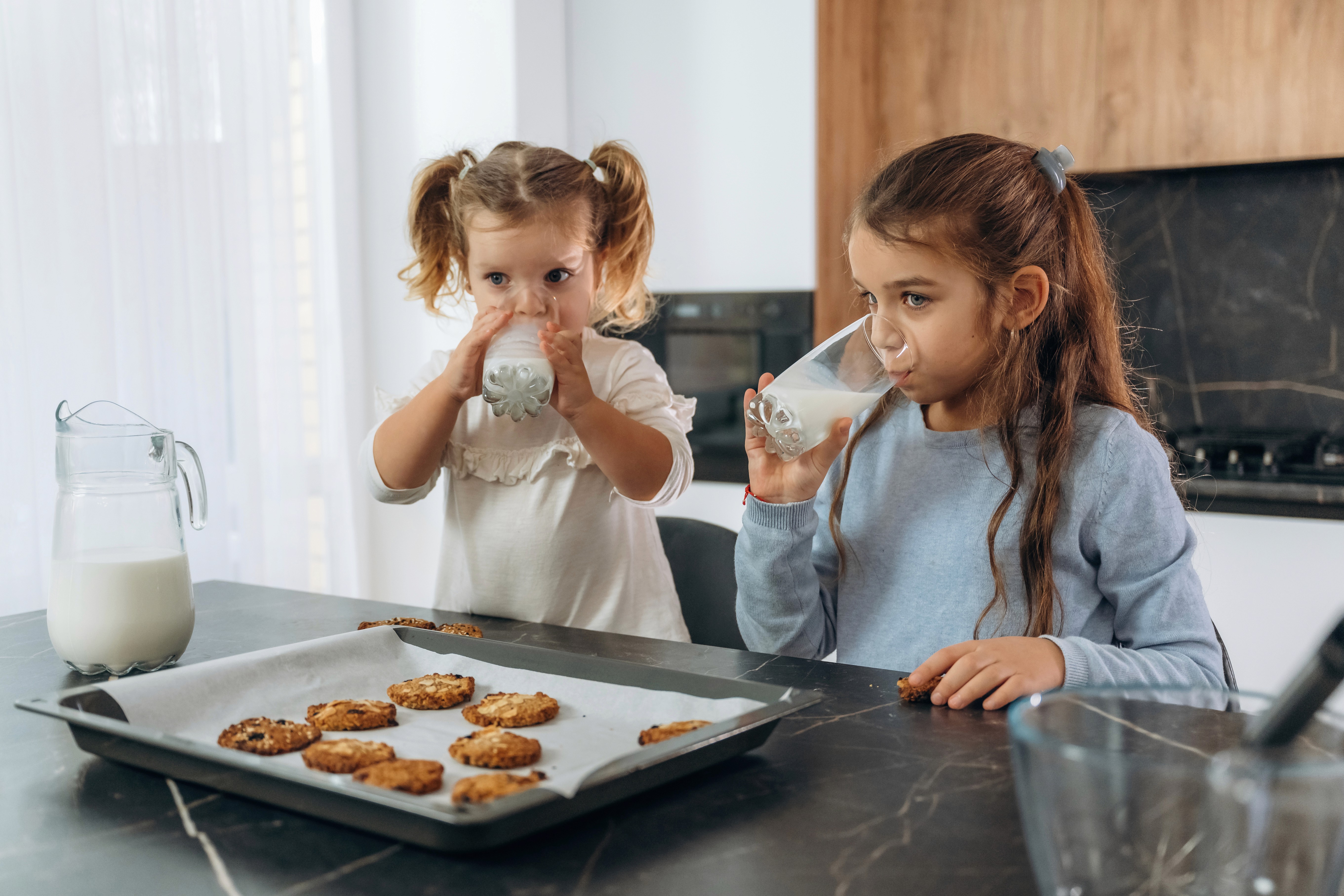 Muscular woman in black athletic wear performing a one-arm handstand against a dark neutral studio background.
