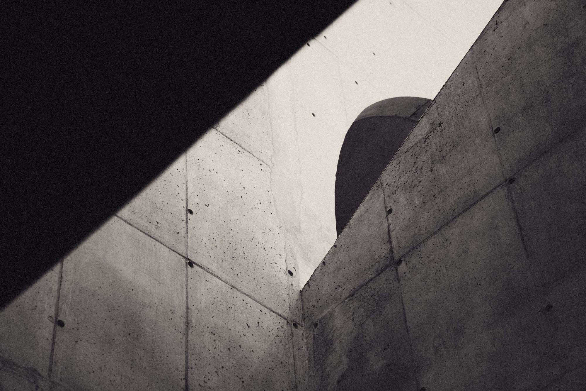 A curved concrete wall cut by a diagonal shadow