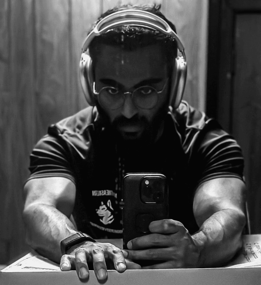 A close-up of a person wearing green-tinted glasses, with a serious expression and smooth skin.