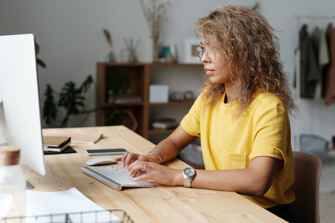 Woman with yellow shirt works at her desk