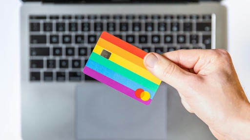 person holding yellow and pink card in front of a computer illustrating the banking