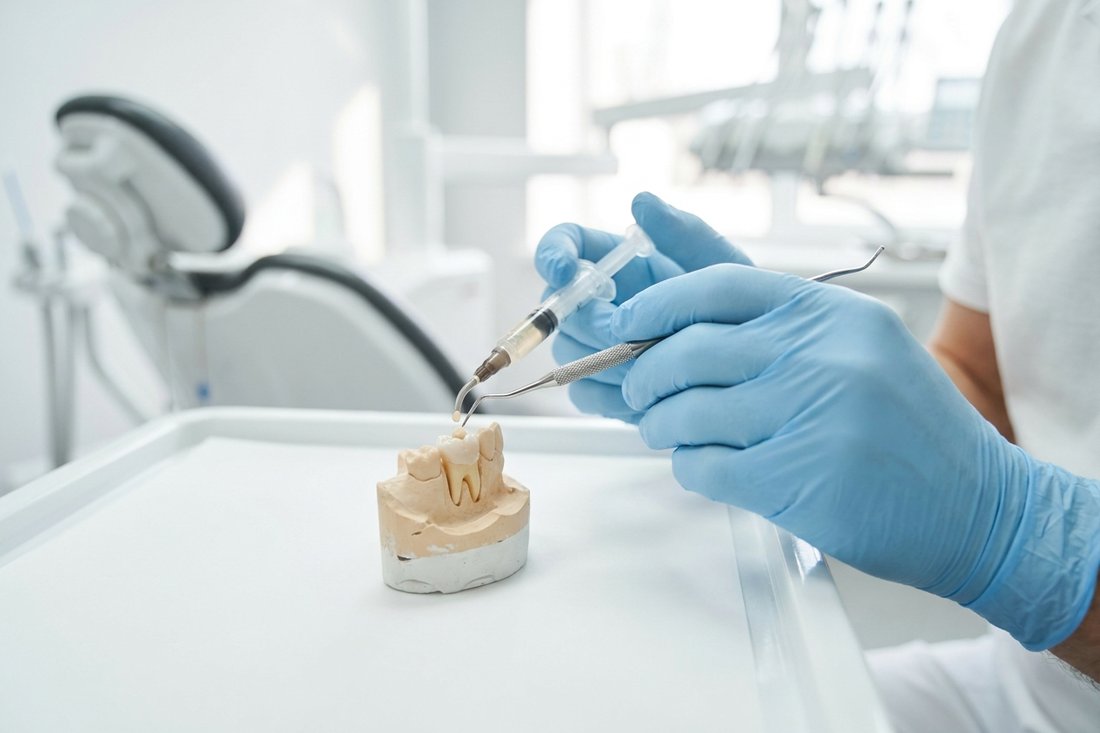 Dentist holding composite resin and a sculpting instrument for dental bonding