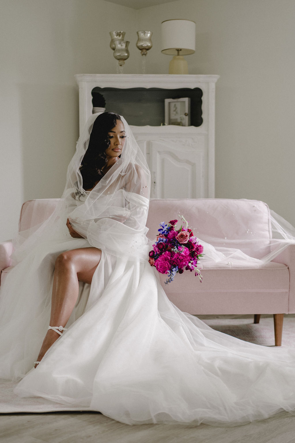 Bride seated with her bouquet on a blush sofa at Daisy Hill.
