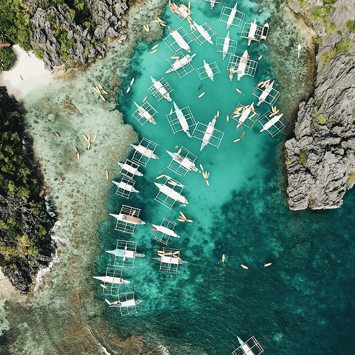 Aerial view of boats moored in turquoise water between rocky island cliffs, Philippines