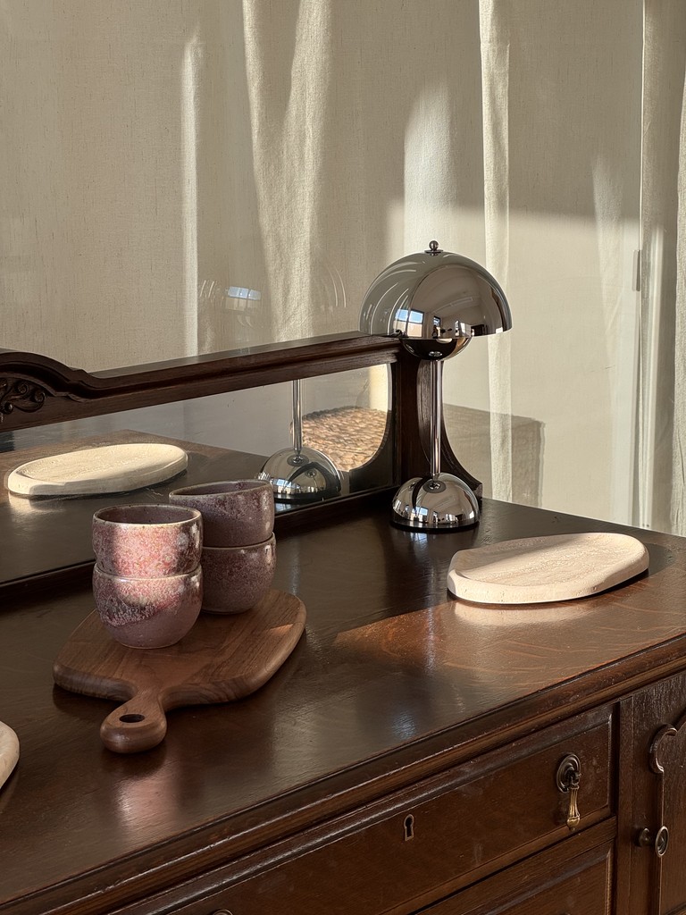 A wooden dresser with a chrome lamp, ceramic cups and stone trays in the SYI studio