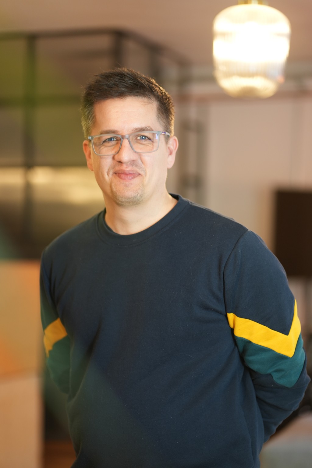 Profile photo, person standing in front of a blue wall wearing a hoodie, a denim jacket and a beanie.